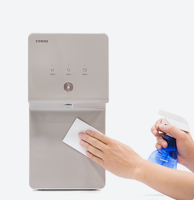 Hand wiping the front panel of a Coway water purifier with a cleaning cloth